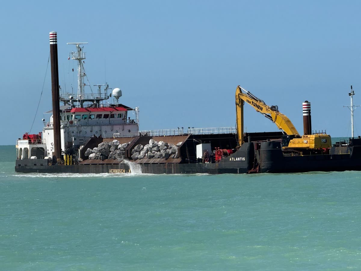 Hopper barge loaded with armour stone and a deck excavator