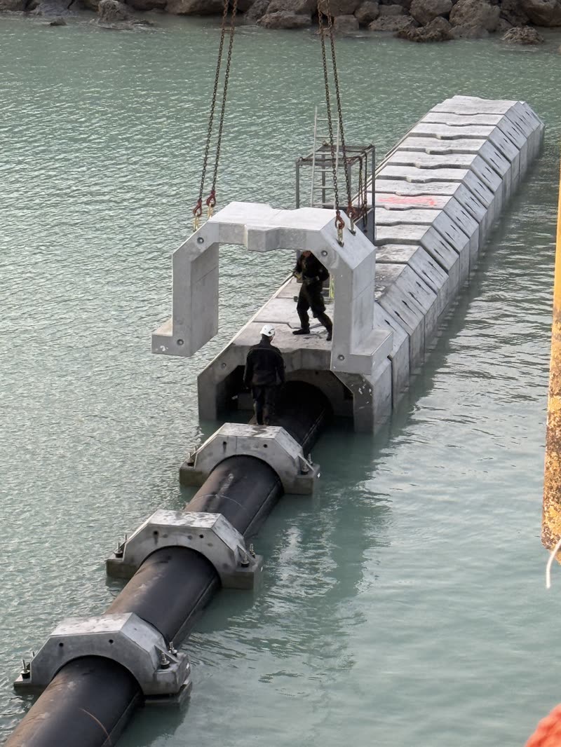 Precast concrete covers being lowered over a marine pipeline