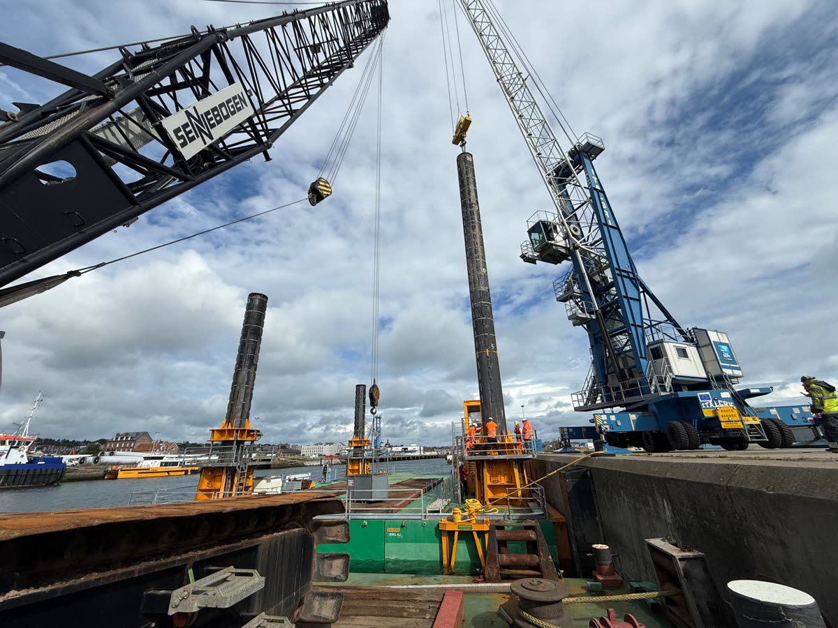 Steel piles being installed from a quay with harbour cranes