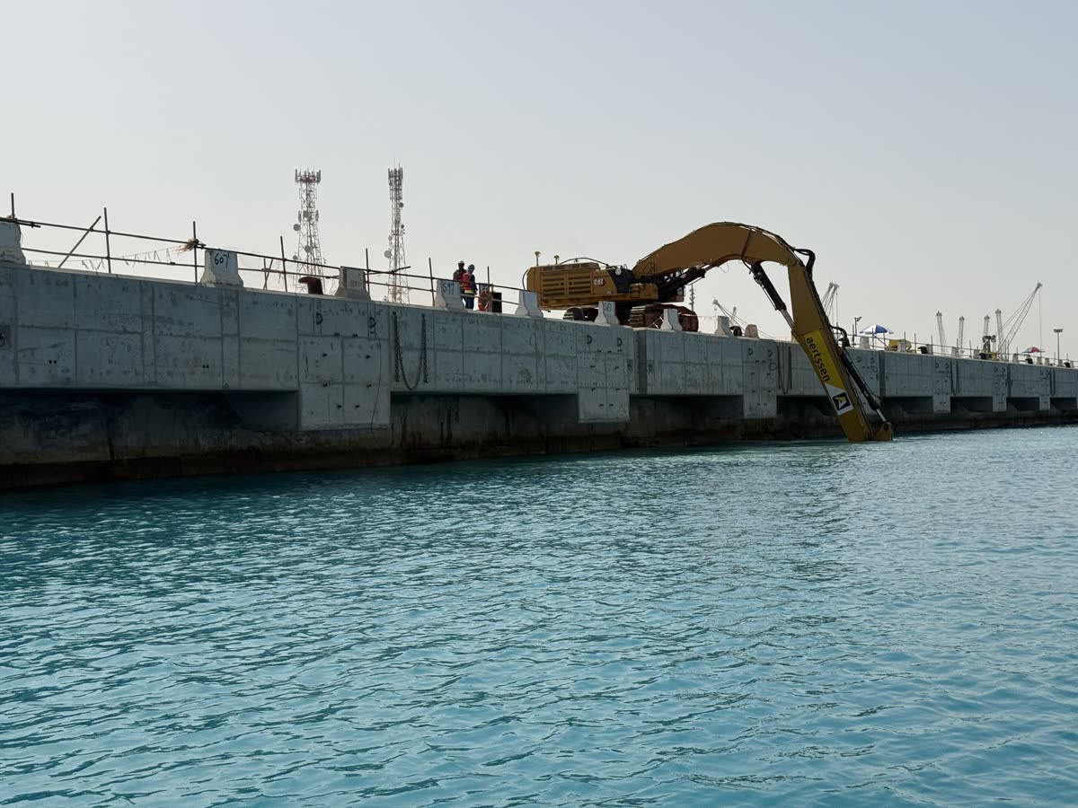 Long-reach excavator working from a concrete quay into the water