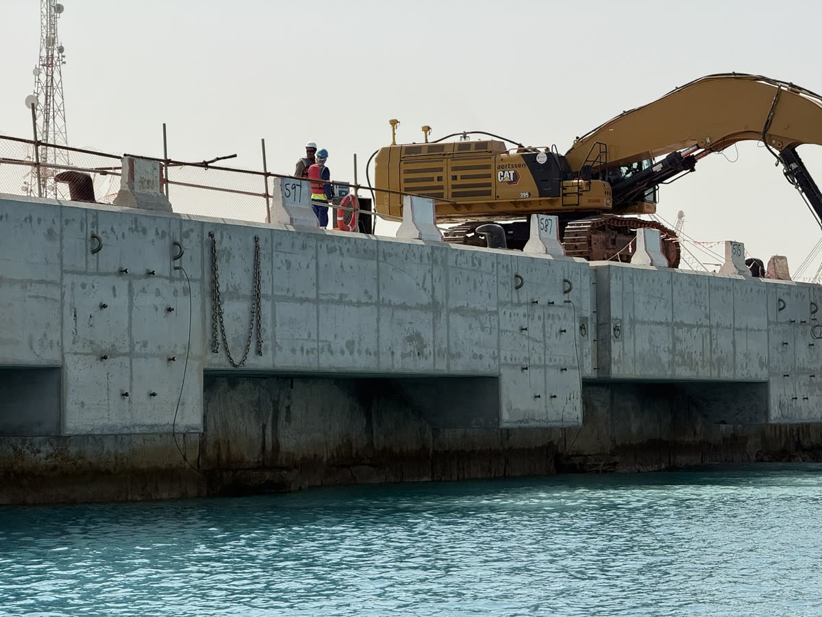 Excavator and crew on a numbered concrete quay wall