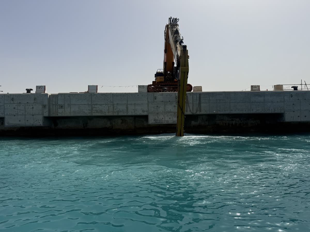 Excavator arm reaching from a quay wall into the water